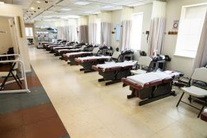 Wide-angle view of NYMDC's physical therapy room with multiple therapy beds and equipment.