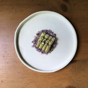 fermented knotweed, labneh, pickled chive blossom, and birch syrup on a ceramic plate
