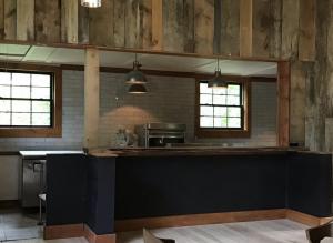 Natural wood and wood walls and dark blue bar with windows showing the homestead beyond