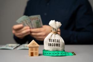 Money bag, miniature house and money in the hands of a businessman