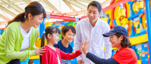 A joyful family interacting with a staff at Legoland Japan Resort.