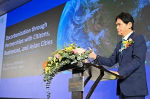 Mayor Yamanaka at podium, presenting on "Decarbonization through Partnerships with Citizens, Businesses, and Asian Cities."