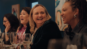 Women laughing around restaurant table at The Humanity Code Dialogue Dinner