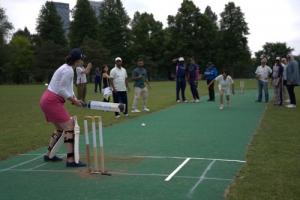 Toronto Mayor Olivia Chow and Nicky Mezo, VP Marketing at TD Bank Group, in cricket action on the cricket pitch during the ceremonial opening game. Mayor id bowling and Nicky is batting , with a crowd of spectators and players visible in the background. T