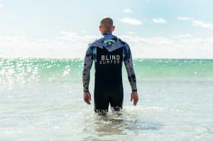 World Champion blind surfer and star of 'The Blind Sea', Matt Formston, wades through the ocean towards an oncoming wave.