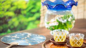 Musubi kiln summer sale collection goldfish in vase next to tea cups placed on a tray with a bamboo fan on the side