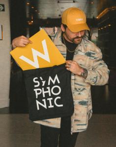 A man holding two bags. One says W and the other says Symphonic.