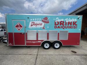 A vehicle with a vibrant wrap advertising a local daiquiri business.