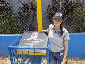 Felicia Greenfield standing with Ronnee Sass Memorial Plaque at Escuela de Gracia