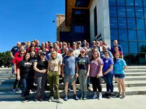 44 individuals stand together outside for a group photo.