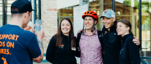 A selfie being taken by a group of people with a man wearing a bike helmet.