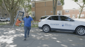 Smiling J. Blanton Plumbing technician walking to a job, representing the company's No Drip Club, 24-hour plumbing service, and water heater flush & maintenance.