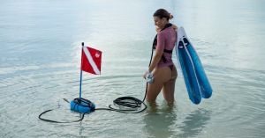 Diver using Nomad dive system with unit floating beside her in the water