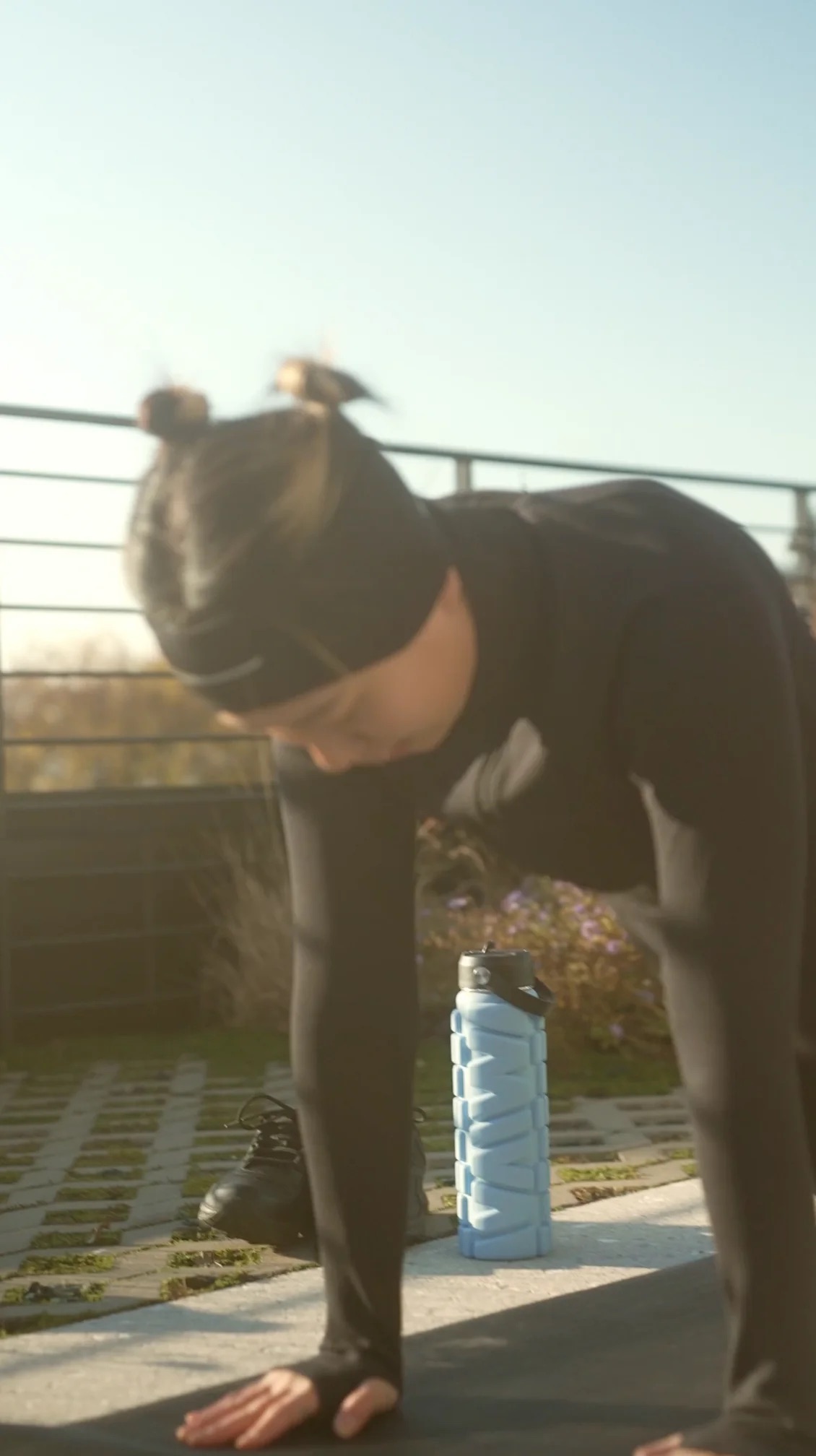 A woman training on a track while using her MIVA Recovery water bottle/foam roller to relieve muscle tension while also staying hydrated.