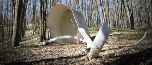 White wood sculpture nestled among trees in the forest.