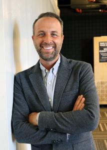 Adam Soliman smiles with arms folded.