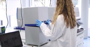 A lab technician operating a real-time PCR analyzer in a modern laboratory setting.