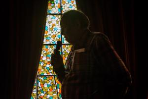 John Lomax III silhouetted by a stain glass window for CD, AMERICAN FOLK SONGS