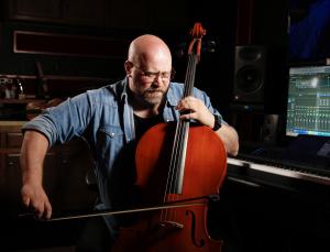 Composer Andrew Scott Bell plays an instrument in his studio