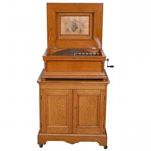 Double comb Regina music box playing 20.5-inch discs (14 included), recently serviced and having outstanding sound, the music box 14 inches by 30 inches set on an oak cabinet (est. $4,000-$6,000).