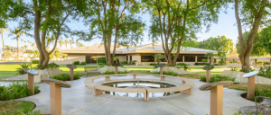 Courtyard with benches and trees in front of a house, providing a peaceful outdoor space.