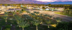 Aerial view of Palm Springs at dusk, with city lights shining and mountains in the background.