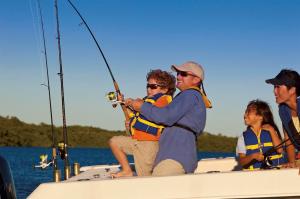 A family wearing life jackets is fishing on a boat