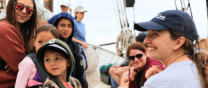 A woman and a child sit together on a boat surrounded by other passengers, enjoying a scenic outing on the water.