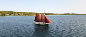 A sailboat featuring striking red sails navigates the serene waters, creating a picturesque maritime view.
