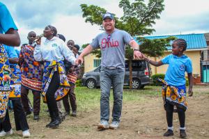 Christopher Lindsey is holding hands with International Samaritan scholarship students in Kenya.