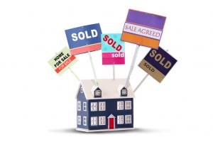 Estate agent house signs for sale and sold on a toy house isolated on a white background