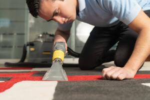 A close-up view of a commercial cleaning technician using specialized equipment to deep-clean a carpet.