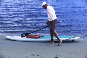 A man, holding a paddle, prepares to go paddleboarding.