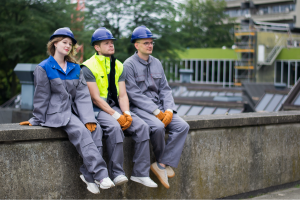 Three people sitting on a ledge, wearing working gear