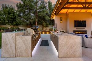 Wendy Glaister's ultimate outdoor kitchen features a gas grill and pizza oven. farmhouse sink, warming drawers, freezer, refrigerator and ice maker within double 12 foot islands.