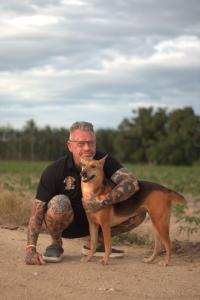 A close-up of Michael J. Baines posing for a photo outside the Sanctuary with one of the dogs