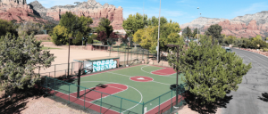 A scenic basketball court located in front of a towering mountain.