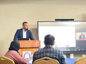 Gustavo Gonçalves presenting research findings on student retention in higher education institutions at a conference in the United Arab Emirates, standing at a podium with a presentation slide in the background.