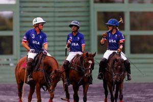 Three arena polo players representing USA discuss pre-game strategy on horseback