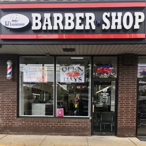 The front of AJ's Barbershop, showing the signs on their windows