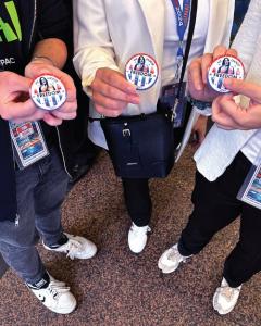 Group of people standing in a sidewalk displaying the pins in their hands.