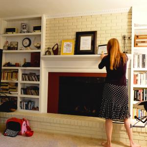 woman adjusting Smile Songs art prints that sing on fireplace mantel