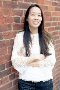 Michelle Kam standing with her arms crossed in front of a brick wall.