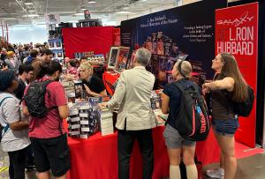 A packed booth in the America's Mart Building 2 at the Atlanta Dragon Con where you can see the Galaxy Press booth with sales staff services public.