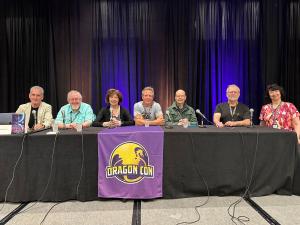 Writers of the Future panel at Dragon Con featuring: John Goodwin, Orson Scott Card, Nancy Kress (Writer Guest of Honor), Hugh Howey, Robert J. Sawyer, S.M. Stirling, and Jody Lynn Nye seated at front of auditorium.