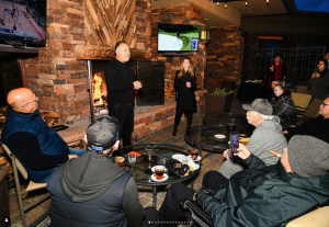 Rich Robledo speaking to guests at a Cigars and Conversation event, fostering an evening of networking and engaging discussions by the fireplace.