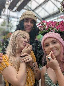 Two girls and a guy are standing in a flower shop with Action Aroma natural corks below their noses, whiffing the aroma with blissful expressions.