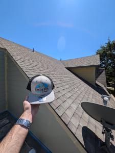 Emerson Roofing hat with a roof background