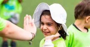 Adventure camper smiling wide while giving their coach a high five.