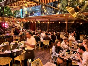 Chic outdoor dining at Pera Soho in SoHo, New York, showcasing Mediterranean-style decor, comfortable seating, and retractable awnings for a year-round al fresco experience, perfect for private events and casual meals.